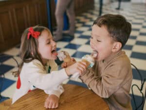 two kids licking each other's ice cream cones at an old fashioned ice cream parlor near Prosper TX