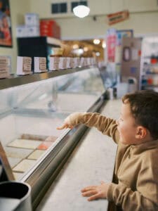 young boy pointing to ice cream flavor at old fashioned ice cream parlor