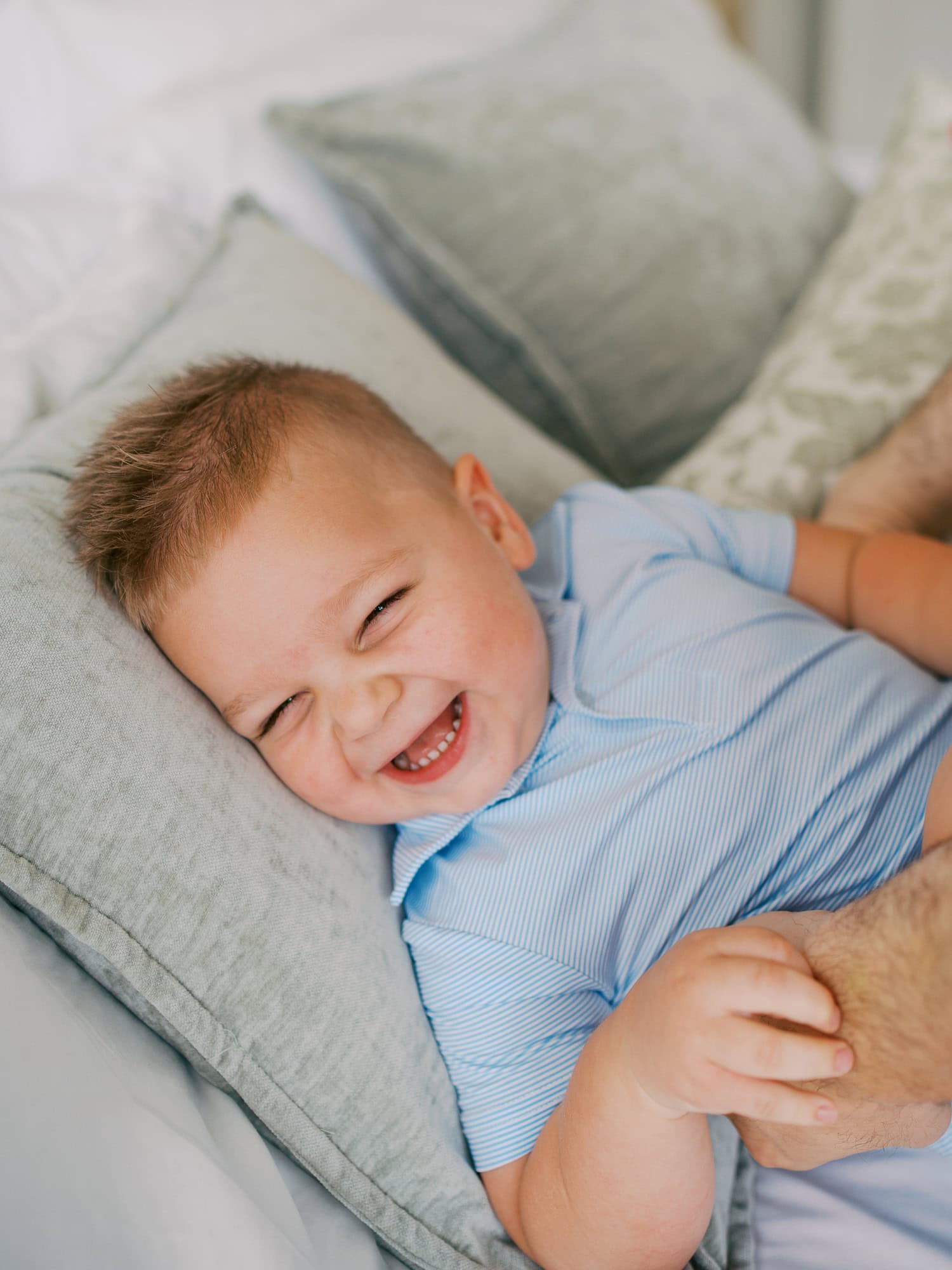 toddler boy laughing while snuggle into a pillow