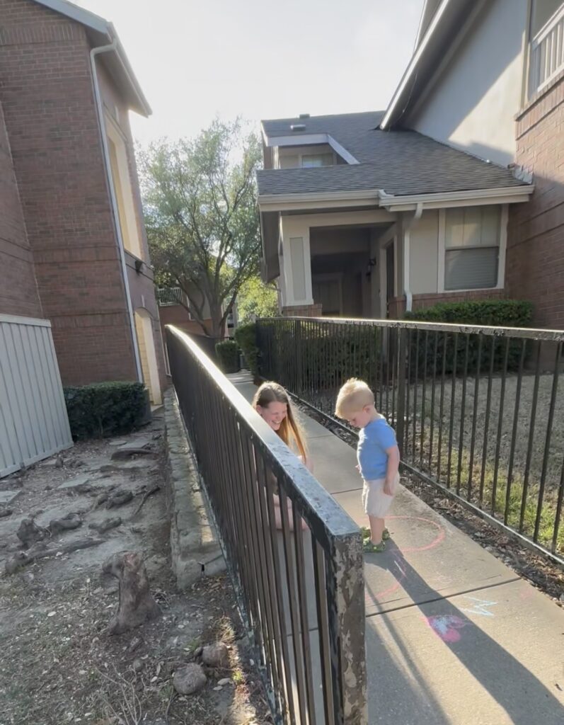 iphone view of image of mother and son outside apartment on a sidewalk