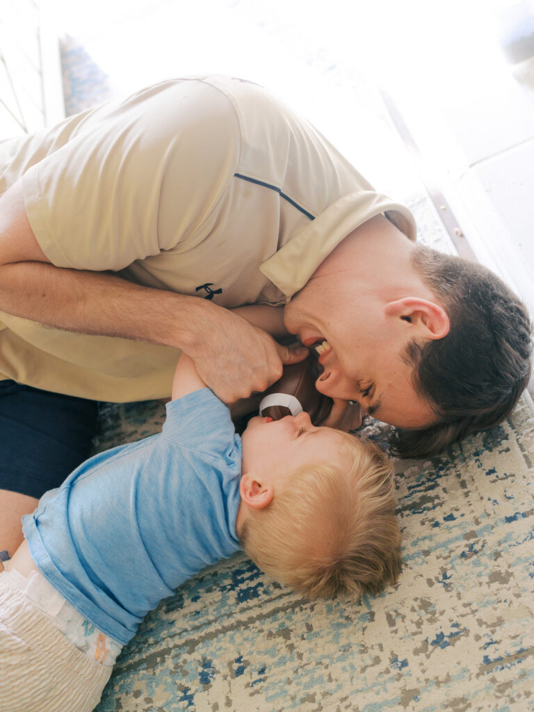 dad and son snuggling on the ground with a football in between that they were tackling each other over